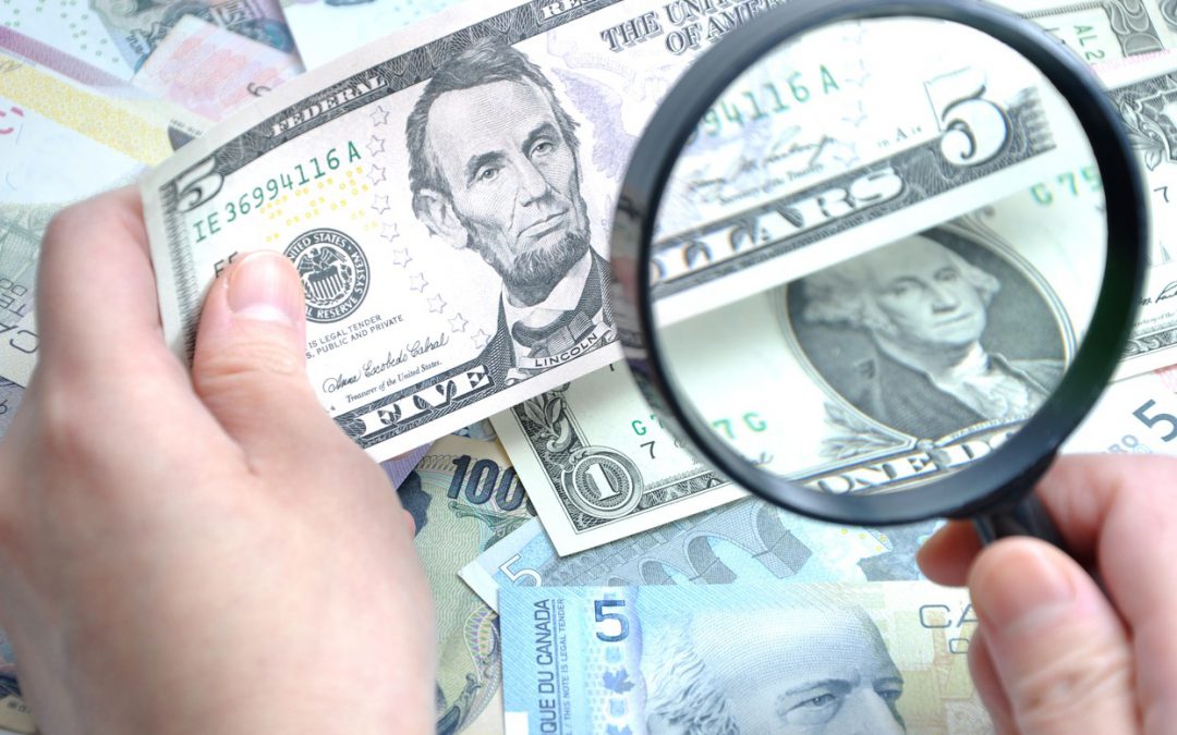 Inspecting Cash with a Magnifying Glass Representing Countermeasure to Counterfeit Currency